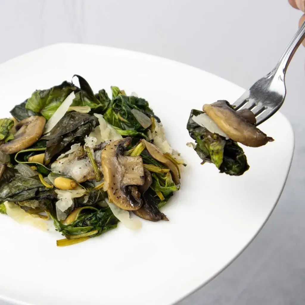 fork with mushroom and cooked sweet potato leaves