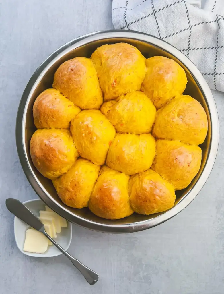 fresh from the oven are a dozen sweet potato rolls in a circular pan